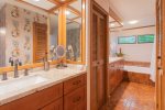 A large, remodeled bathroom features new his-and-her vanities with custom cabinets, a full-length mirror and newly refinished oversized soaking tub